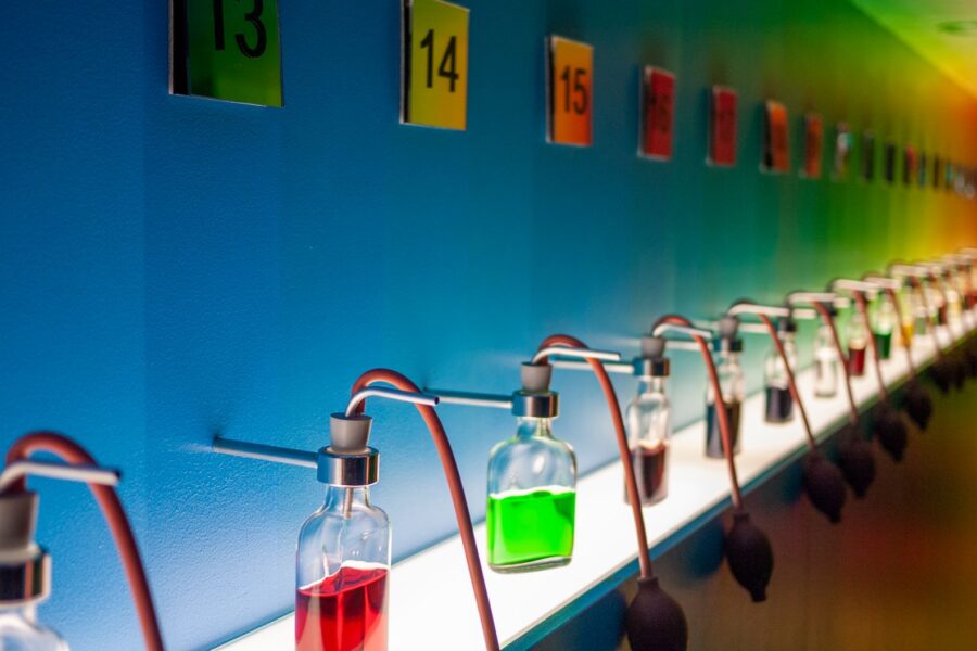 Row of glass bottles with colored liquids in a vibrant lab setting.